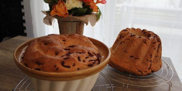 deux kougelhopfs cuits devant une bouquet de fleurs oranges
